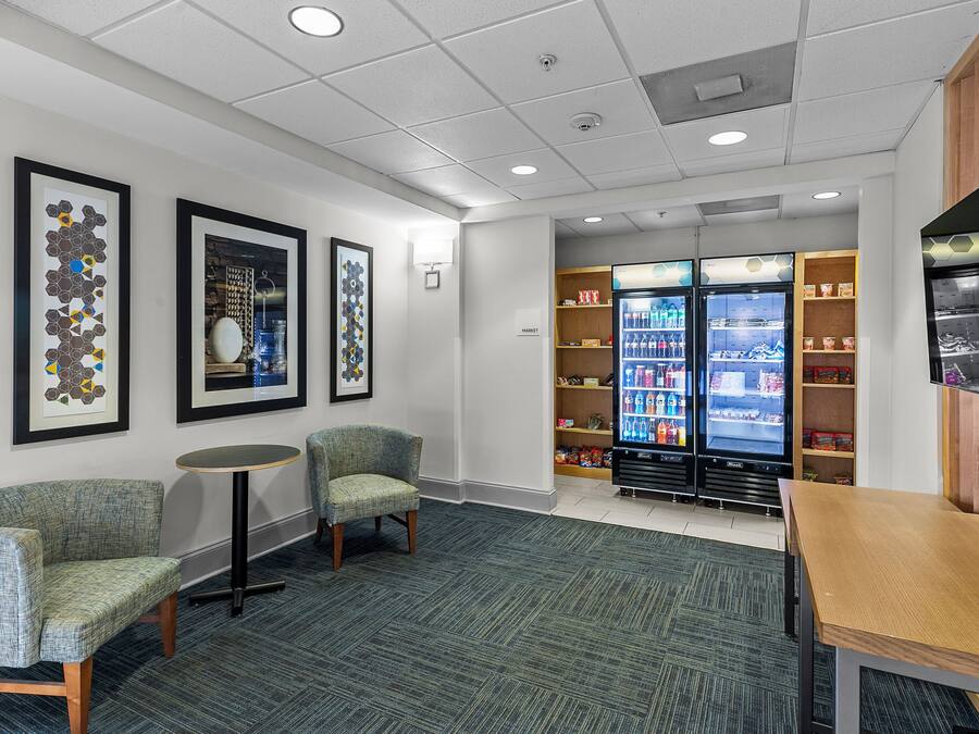 A lobby with seating, a vending machine, and a wall-mounted fire alarm.