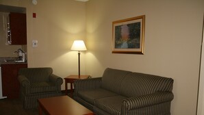 Ein Wohnzimmer mit gestreifter Möbel, einer Lampe und einem Bild an der Wand.