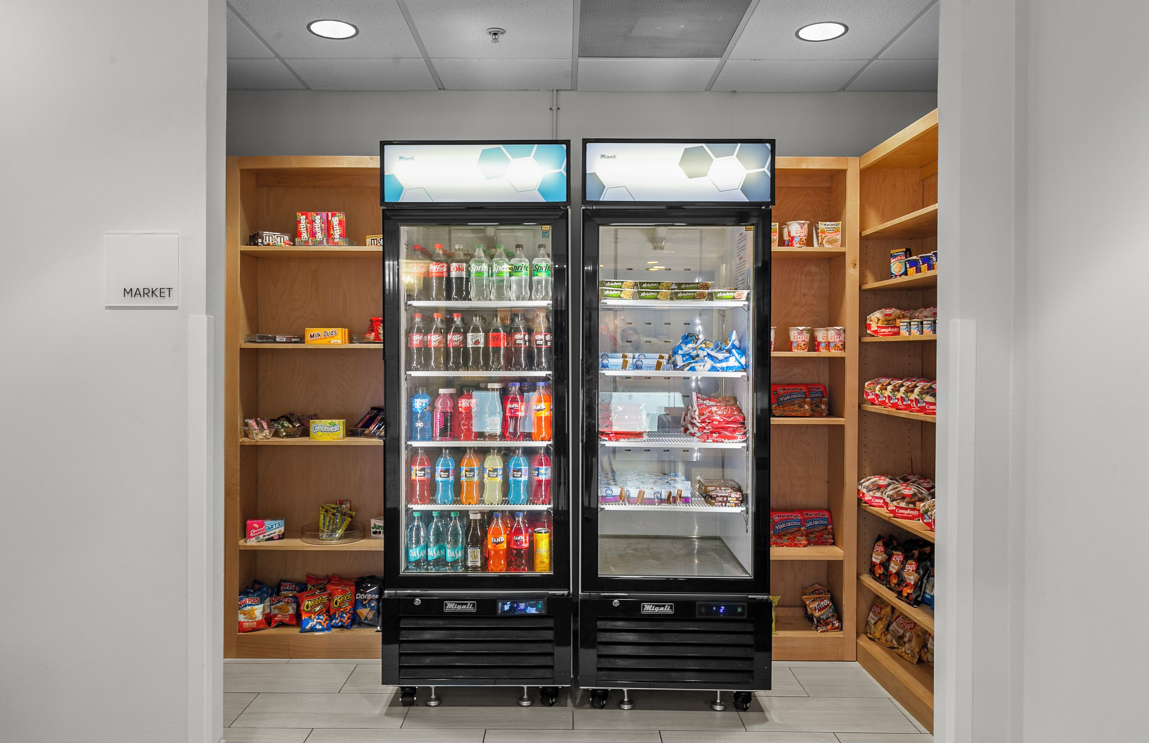 Een automatenruimte met twee automaten, planken vol snacks en een 'MARKET' bord.