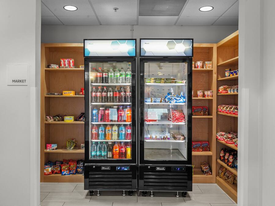 Een automatenruimte met twee automaten, planken vol snacks en een 'MARKET' bord.
