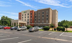 Een Holiday Inn Express hotel met een parkeerplaats en meerdere auto's er voor geparkeerd.