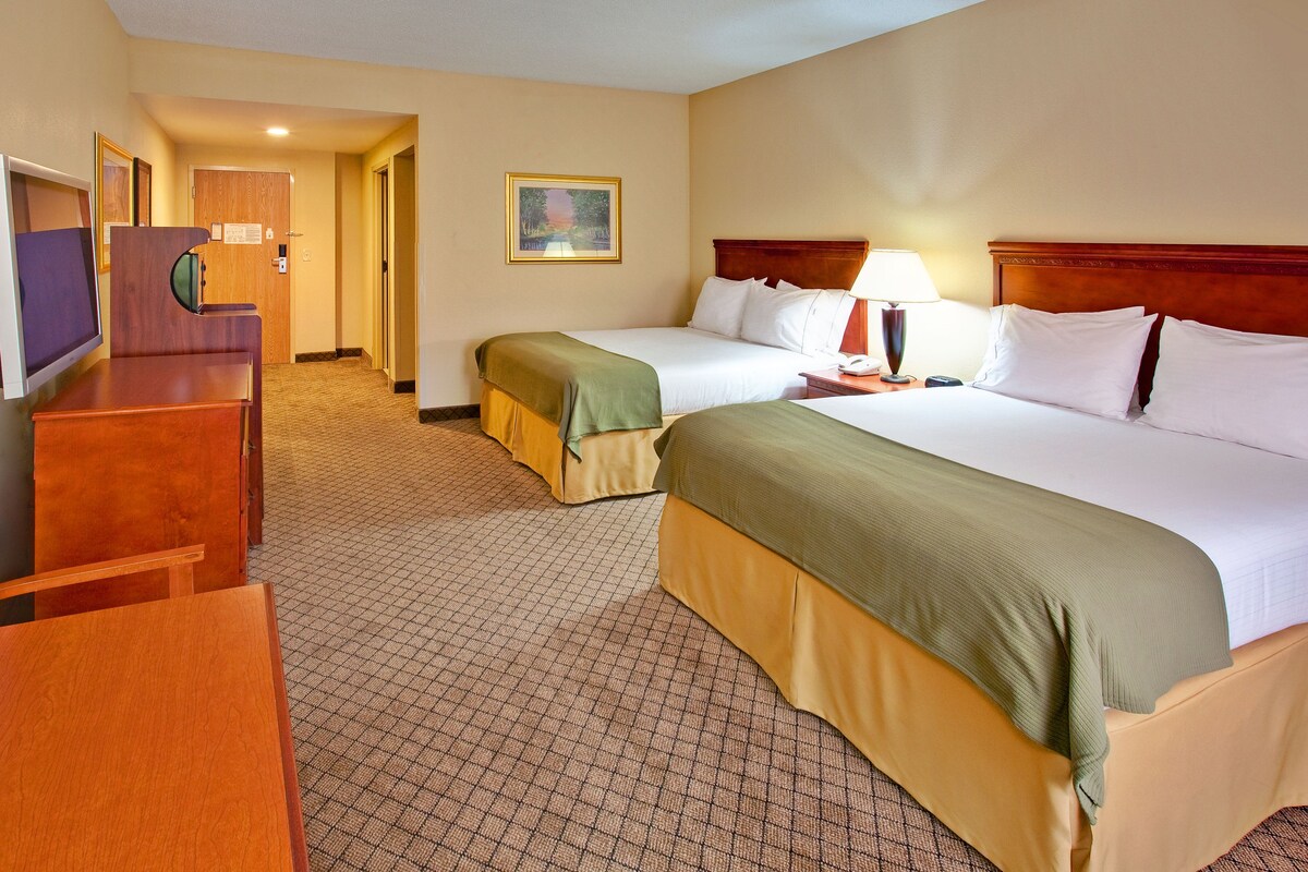 A hotel room with two beds, a desk, and a television.