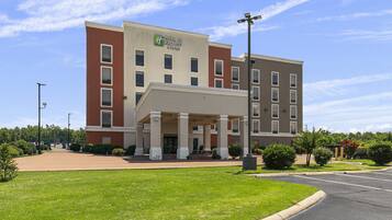 A Holiday Inn Express & Suites building with a covered entrance, multiple windows, and a parking lot.