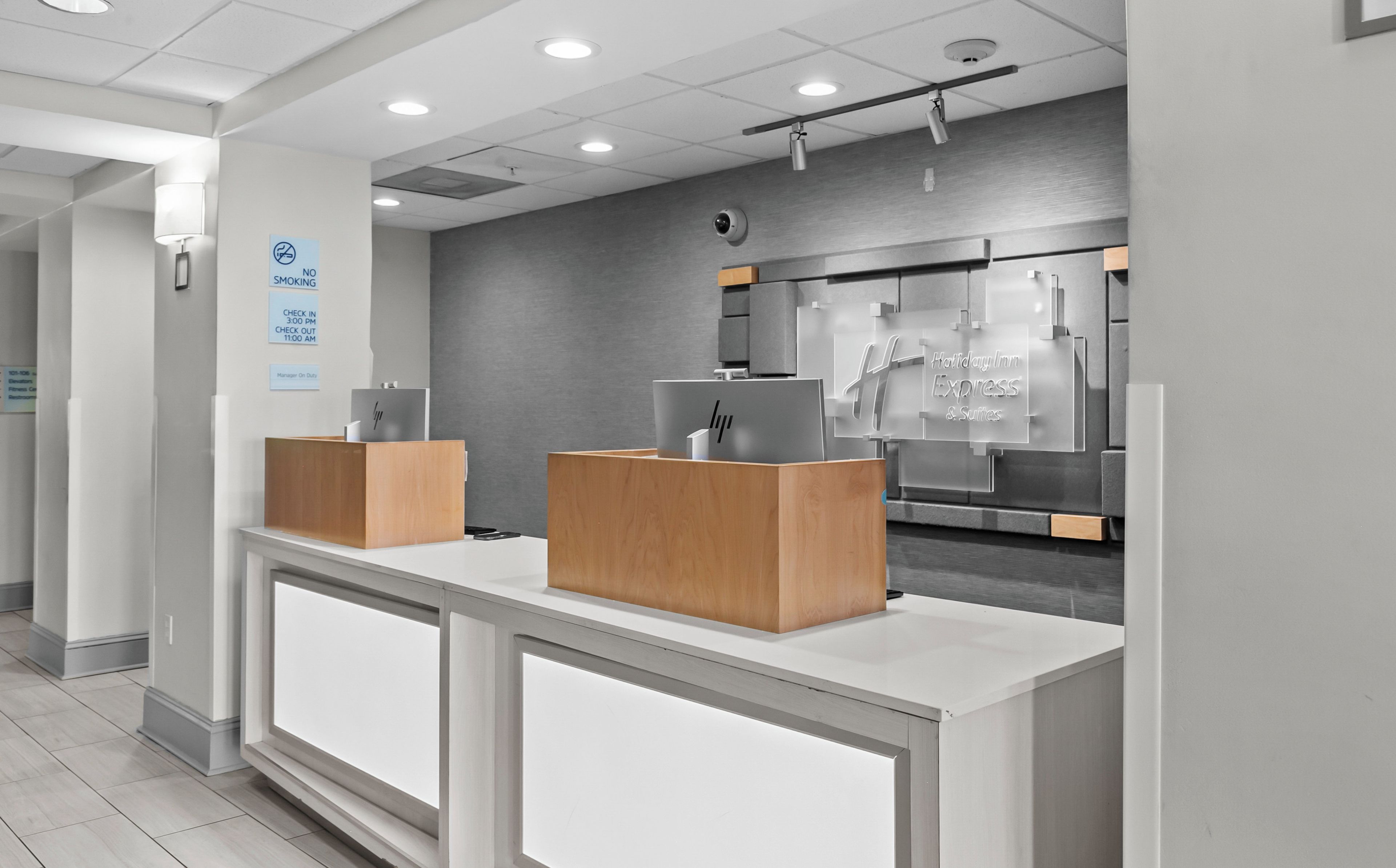A reception desk with a check-in counter, a security camera, and a sign indicating no smoking.
