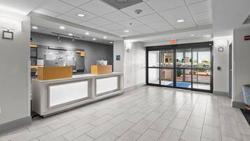 A reception area with a counter, a fire alarm, and a glass door leading outside.