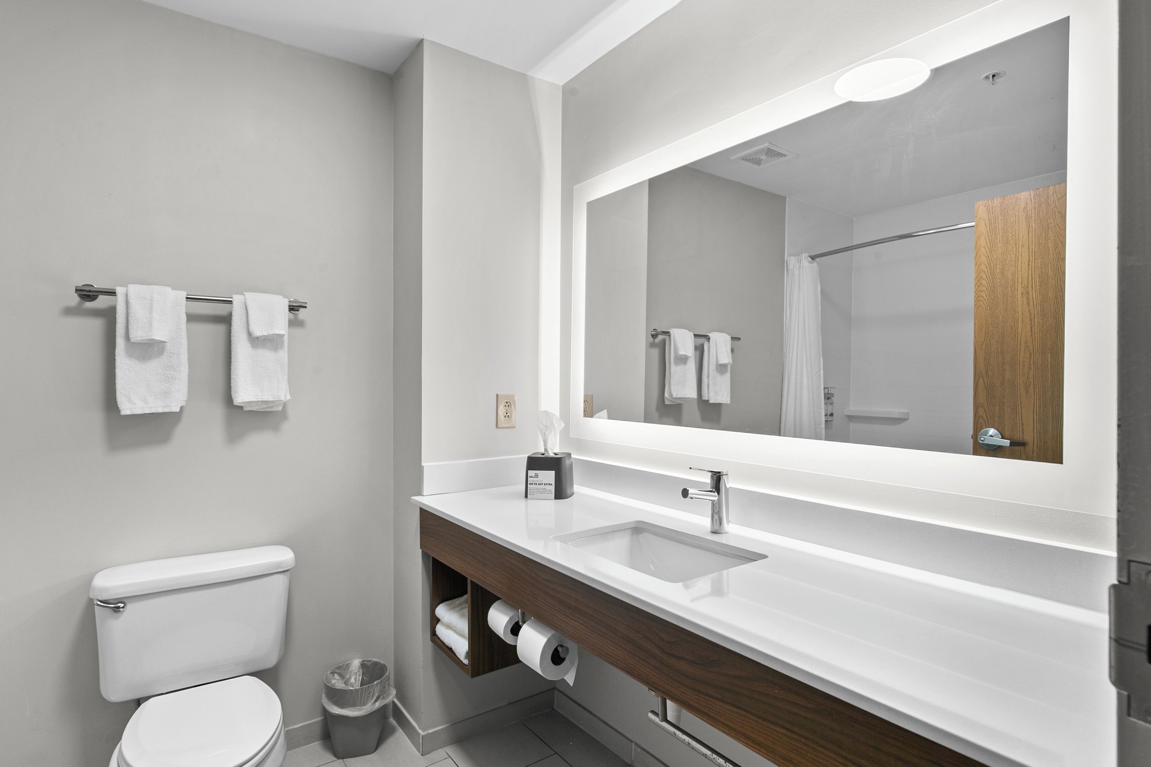 A modern bathroom with a toilet, sink, and mirror.