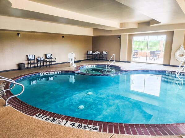 A swimming pool with a 4 ft 6 in depth marking, a lifeguard chair, and a poolside area with chairs and tables.