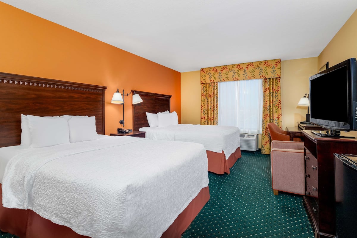 Une chambre d’hôtel avec deux lits, une télévision, un bureau et une chaise.