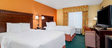A hotel room with two beds, a television, a desk, and a chair.