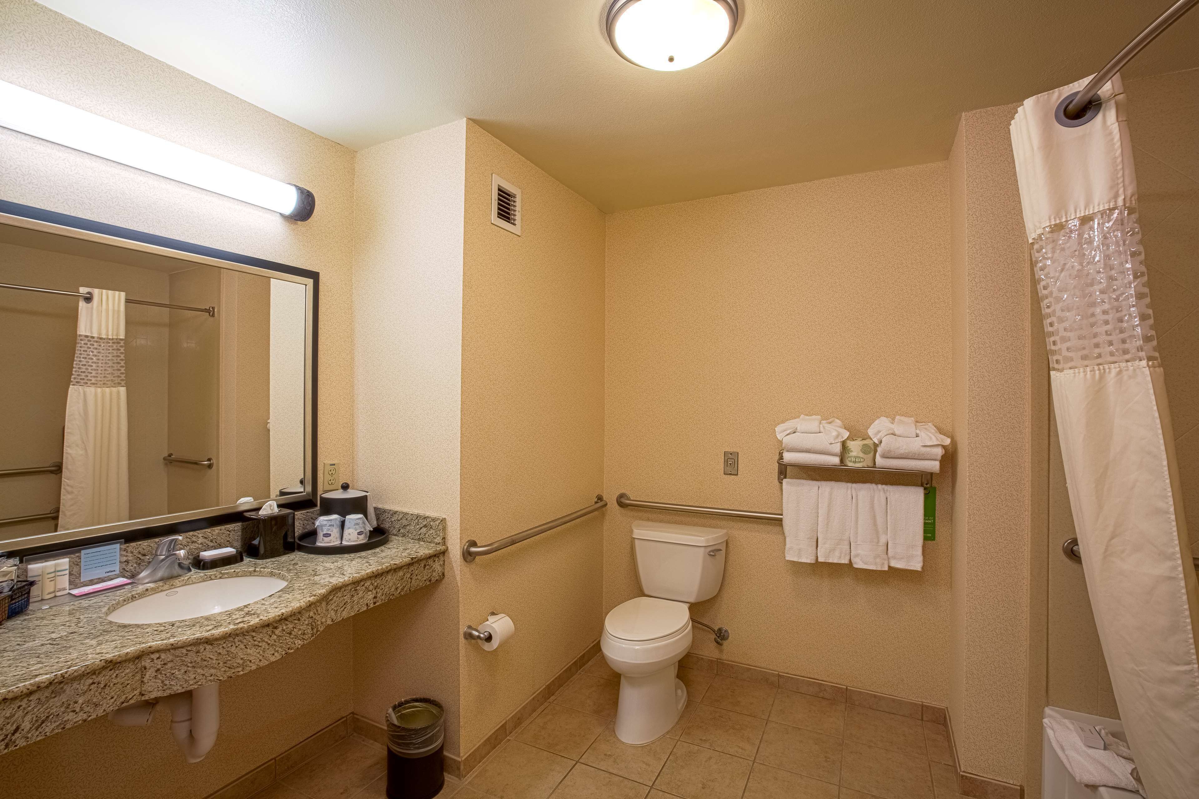 Une salle de bain équipée d’un lavabo, de toilettes et d’une douche. On y trouve des serviettes et des articles de toilette sur le comptoir.