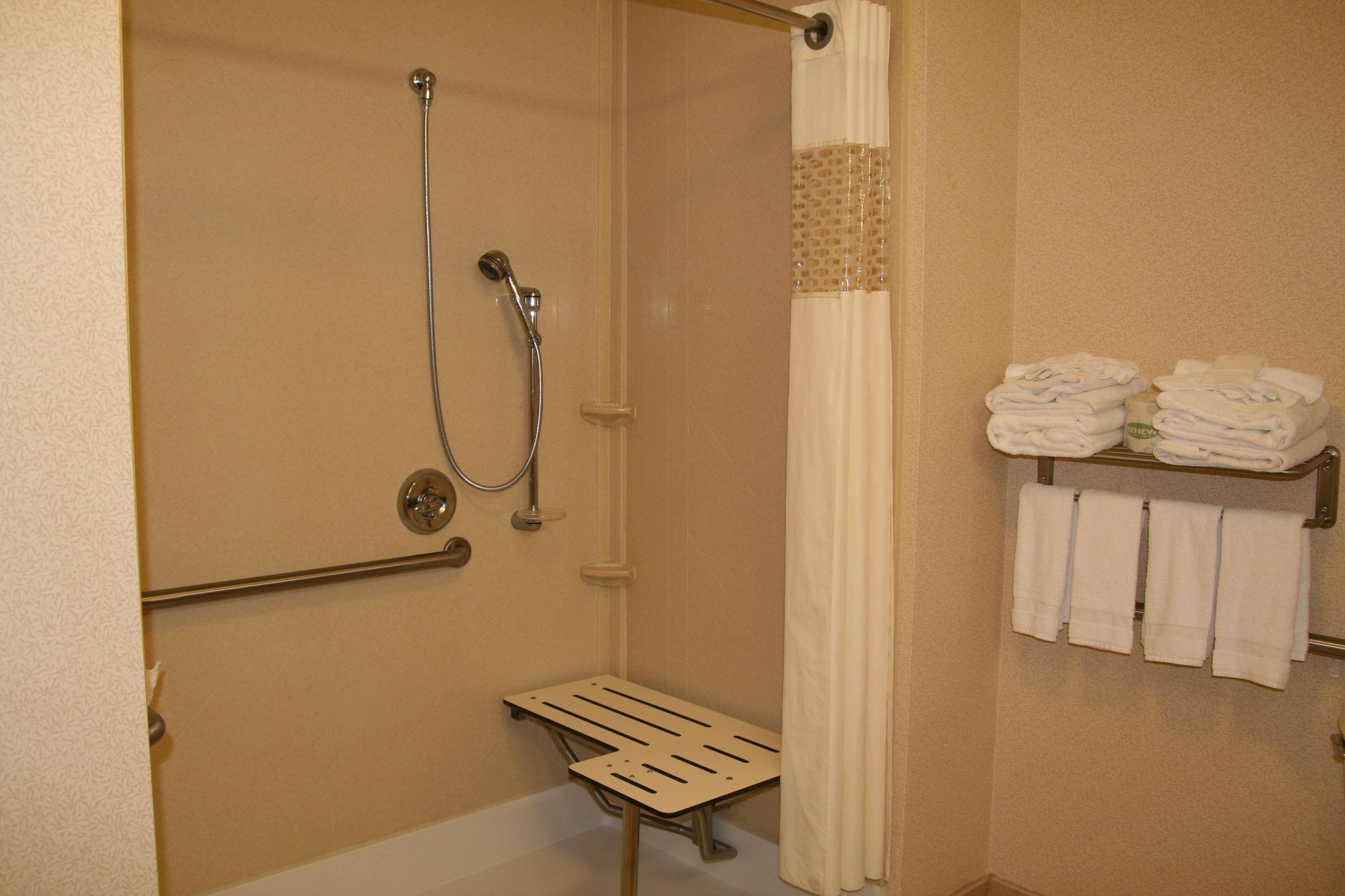 A shower area with a handheld showerhead, a glass-enclosed shower, and a towel rack with folded towels.