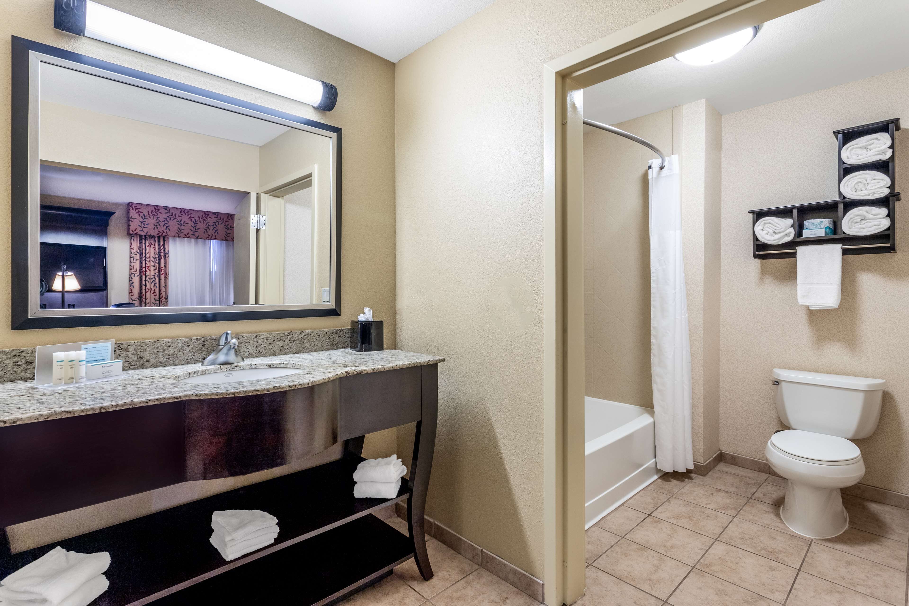 A bathroom with a sink, mirror, toilet, and shower.