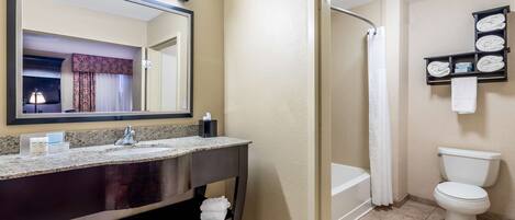 A bathroom with a sink, mirror, toilet, and shower.