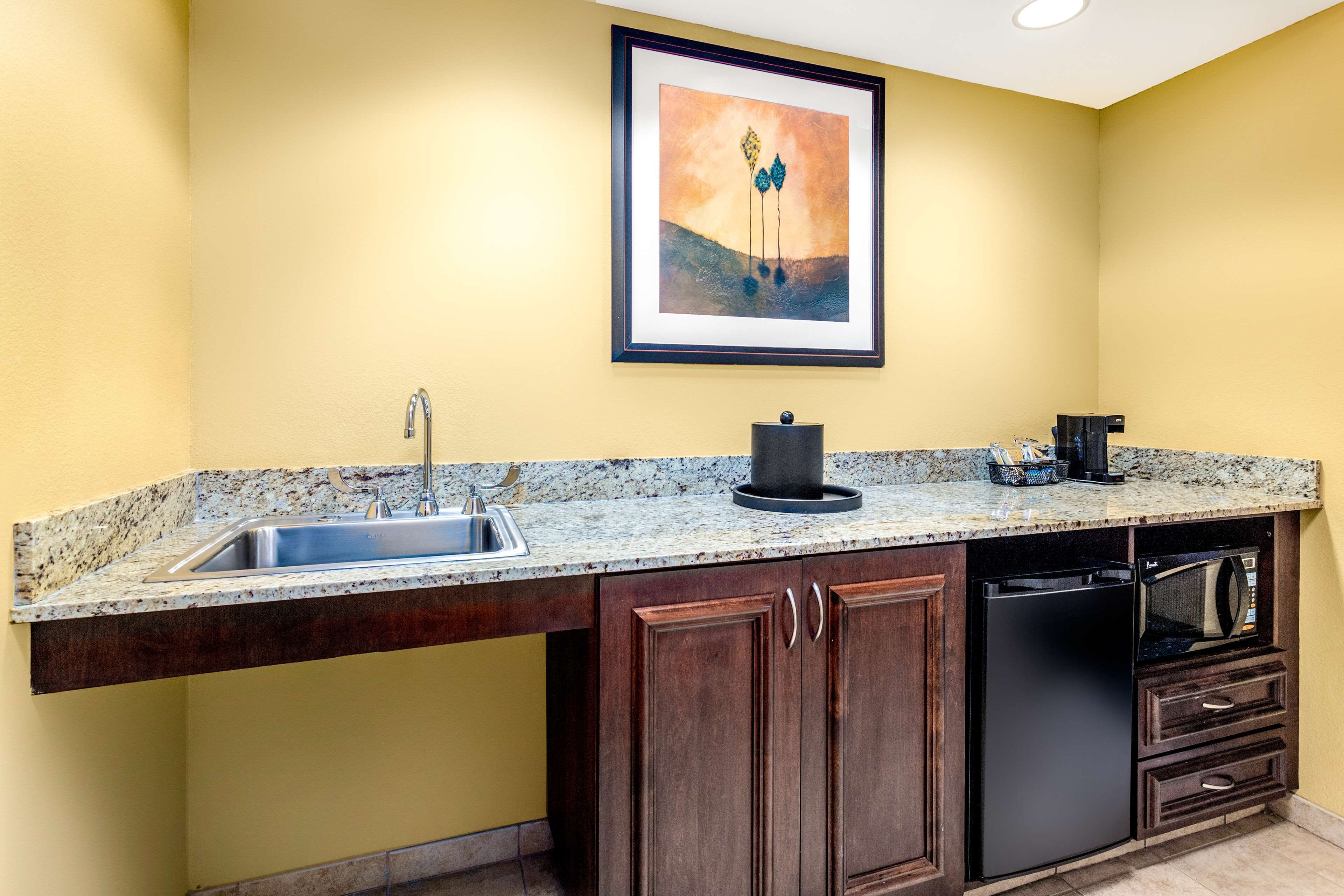 A kitchen with a granite countertop, stainless steel sink, and a black dishwasher.