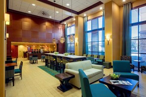 Un vestíbulo amplio con zona de comedor central, asientos cómodos y ventanas grandes.
