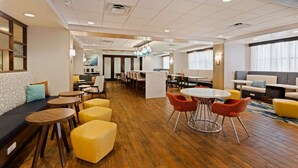 A hotel lobby with a wooden floor, seating areas, and a reception desk. - Hampton Inn Jacksonville-I-295 East/Baymeadows (Jacksonville)