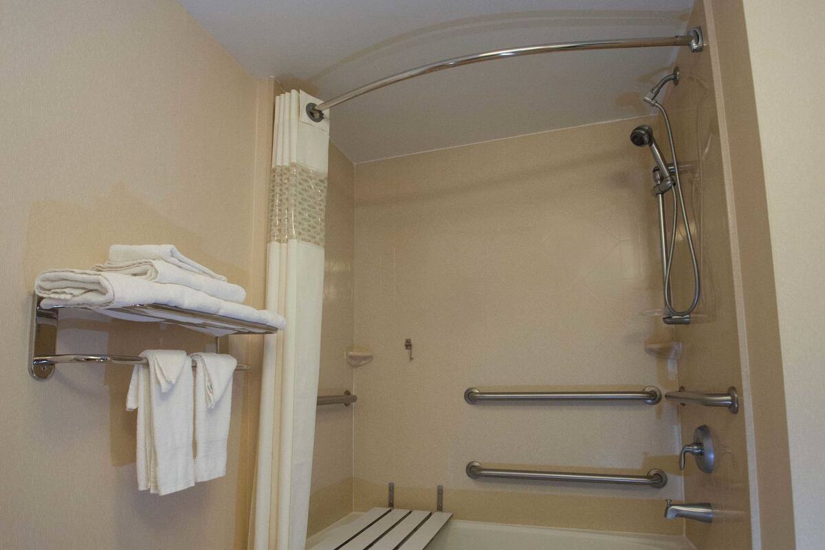 Une salle de bain équipée d’une baignoire, d’une douche et d’un porte-serviettes avec des serviettes pliées.