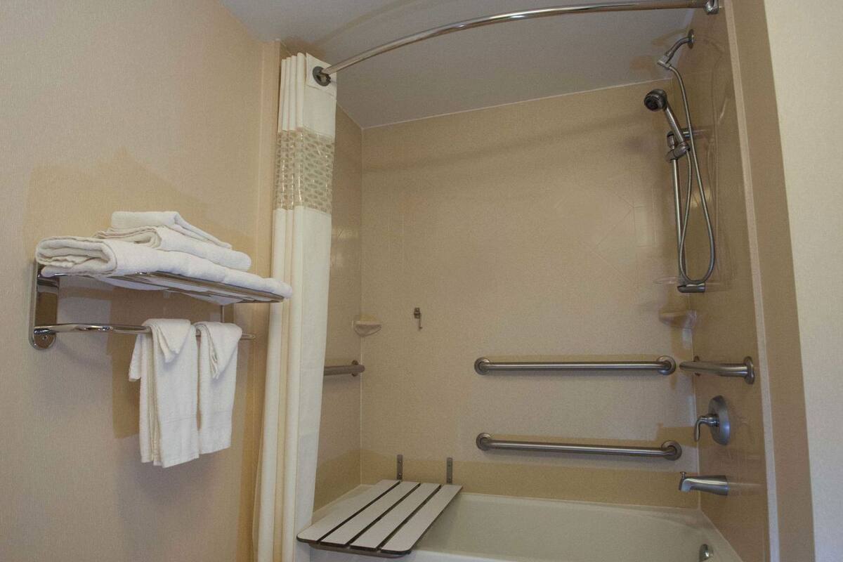 Une salle de bain équipée d’une baignoire, d’une douche, d’un porte-serviettes et d’une barre d’appui.
