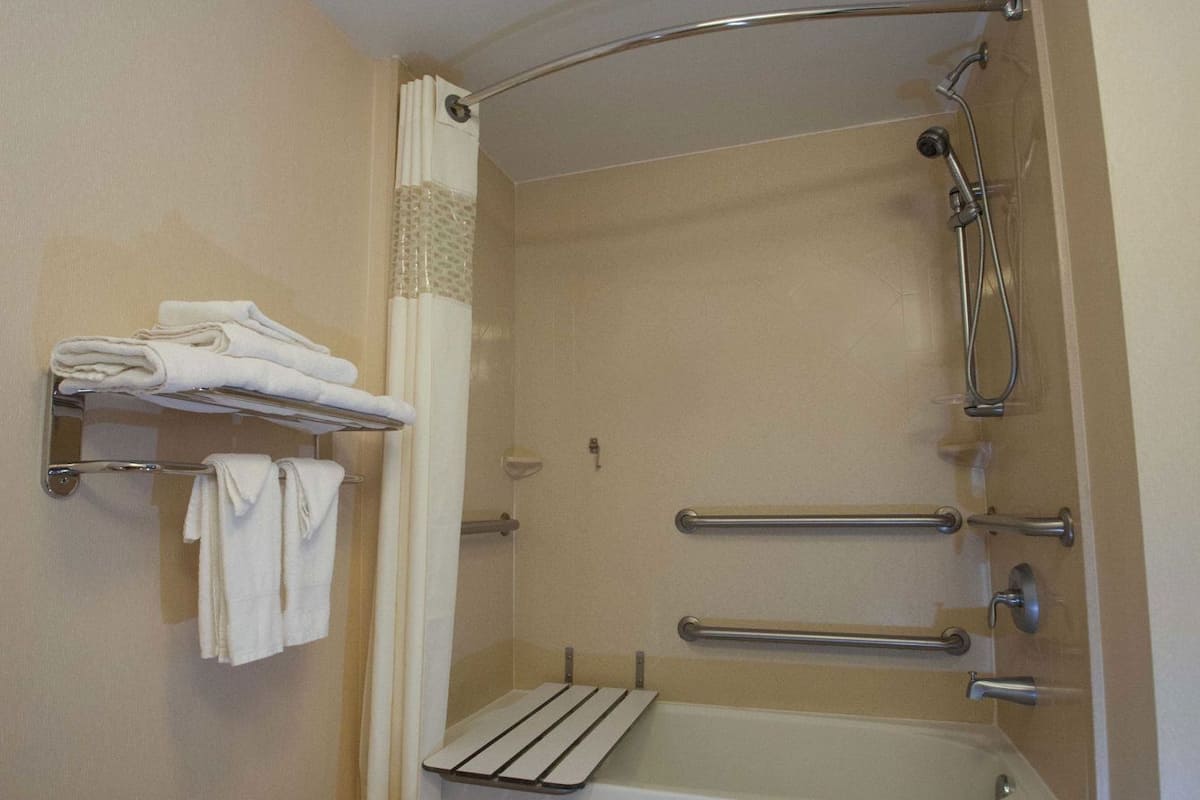 Une salle de bain équipée d’une baignoire, d’une douche, d’un porte-serviettes et d’une barre d’appui.