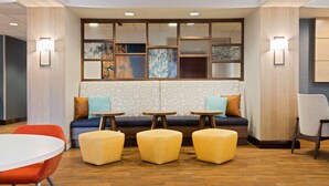 A modern hotel lobby with a seating area, wooden flooring, and wall-mounted lighting. - Hampton Inn Jacksonville-I-295 East/Baymeadows (Jacksonville)
