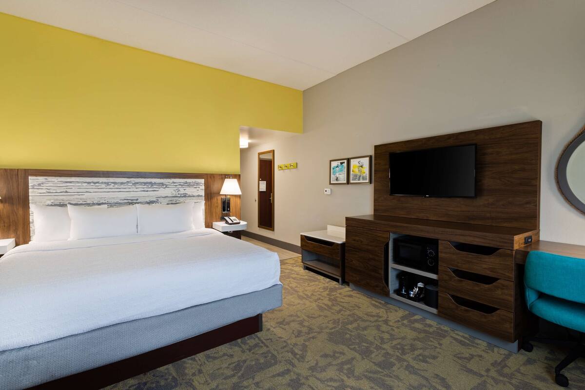 Une chambre d’hôtel comprenant un lit, un bureau, une chaise, une télévision et une salle de bain.