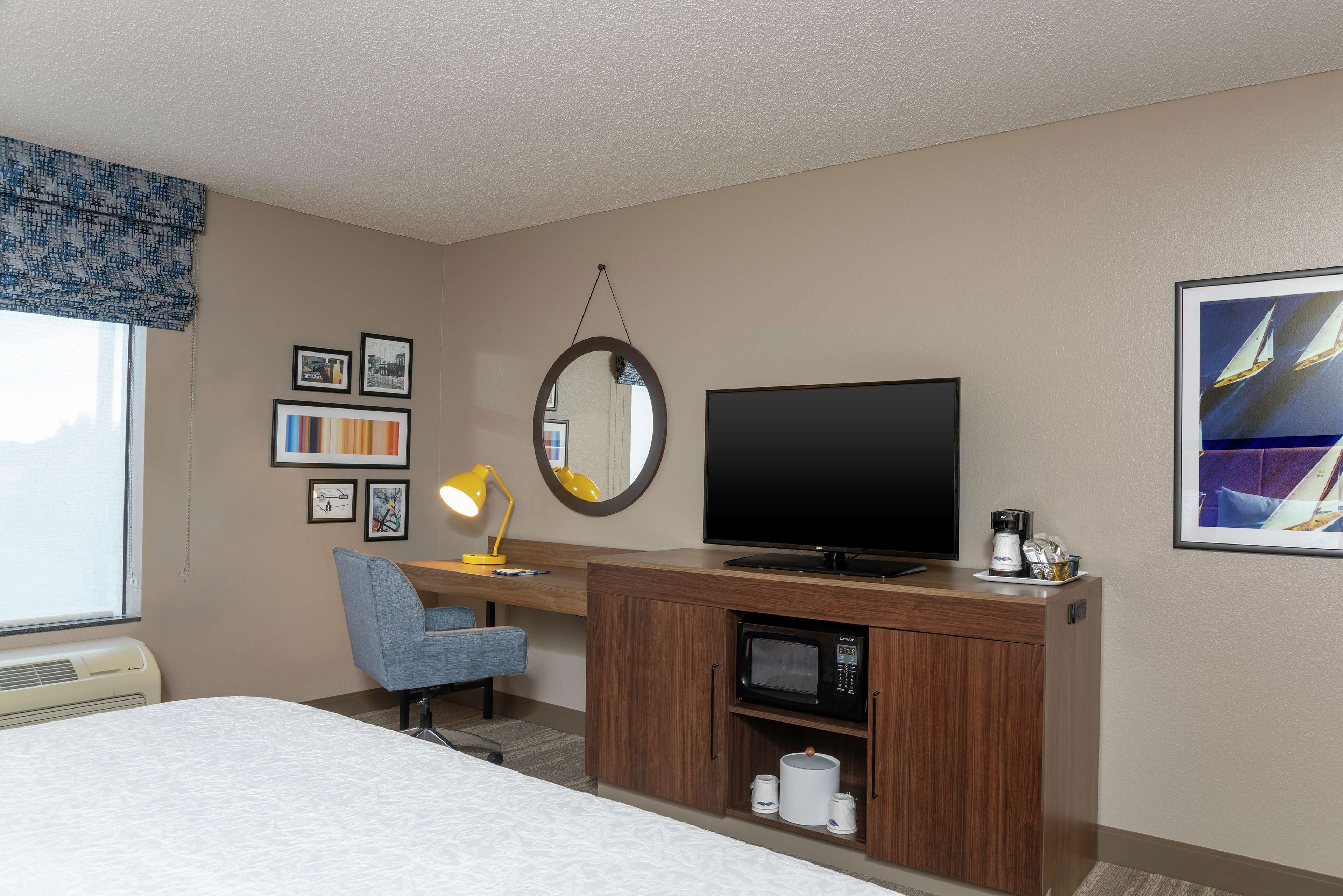 Une chambre d’hôtel comprenant un lit, un bureau avec une télévision, un four à micro-ondes, une chaise et une fenêtre donnant sur une vue de voiliers.