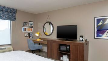 Une chambre d’hôtel comprenant un lit, un bureau avec une télévision, un four à micro-ondes, une chaise et une fenêtre donnant sur une vue de voiliers.