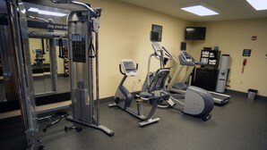 A gym with various exercise machines, a mirror, and a television on the wall. - Hampton Inn Warsaw (Warsaw)