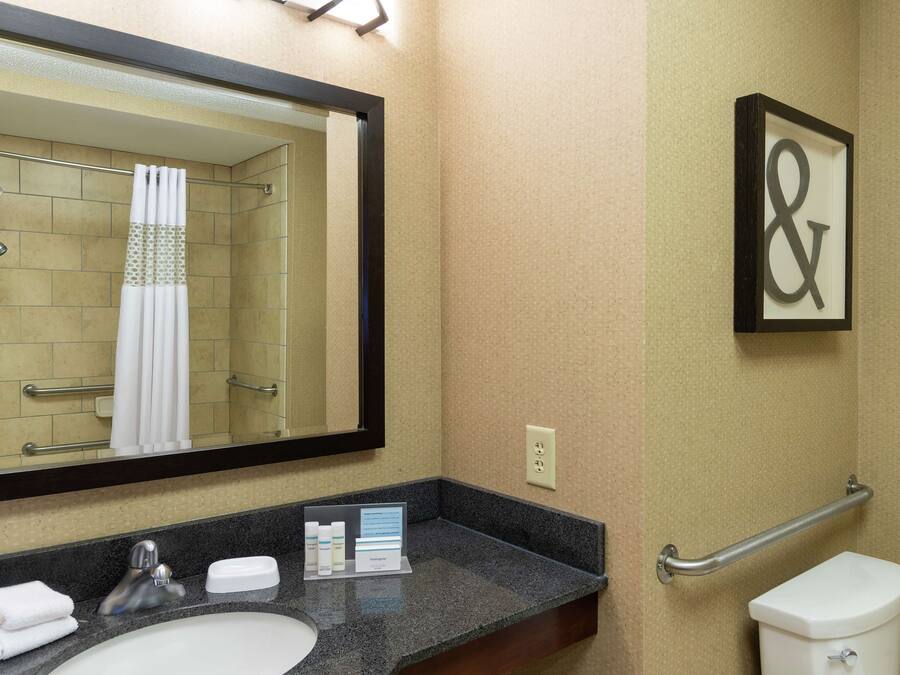 Un baño con lavamanos, espejo, inodoro y ducha.