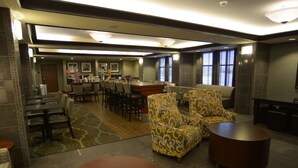 A spacious hotel lobby with a dining area, seating arrangements, and a bar. - Hampton Inn Warsaw (Warsaw)