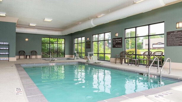 An indoor swimming pool with clear water, surrounded by windows and chairs. - Hampton Inn Warsaw (Warsaw)