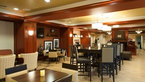 A hotel dining area with wooden paneling, a large dining table, and several chairs. - Hampton Inn Enterprise (Enterprise)