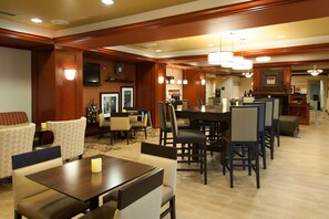 A hotel dining area with wooden paneling, a large dining table, and several chairs. - Hampton Inn Enterprise (Enterprise)