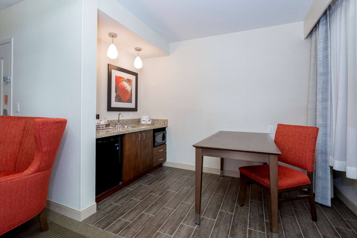 A compact kitchen with a dining table and chairs, a microwave, and a sink.