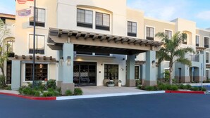 A hotel entrance with a covered patio, a flag, and a sign indicating a pet-friendly policy. - Hampton Inn Santa Barbara/Goleta (Goleta)