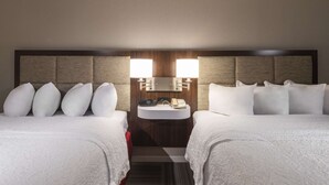 Une chambre d’hôtel avec deux lits, une table de chevet, un lavabo intégré et un miroir.