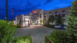 Un hôtel Hampton Inn au design moderne, doté d’une entrée bien éclairée et d’un espace de stationnement.