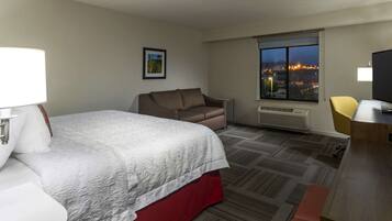 Una habitación de hotel con cama, sofá, escritorio y ventana con vista a la ciudad.