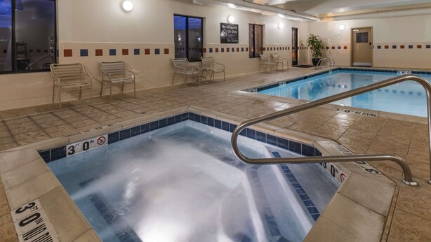 Une piscine intérieure dont la profondeur est indiquée par un repère de 30 pouces, avec des chaises longues et un panneau indiquant qu’il est interdit de plonger.