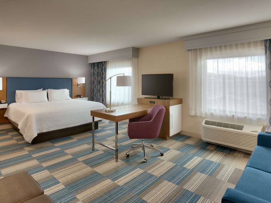 Une chambre d’hôtel équipée d’un lit, d’un bureau, d’une chaise, d’une télévision et d’un appareil de climatisation.