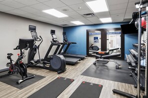 Une salle de sport équipée de vélos d’appartement, de tapis de course et d’appareils de musculation.