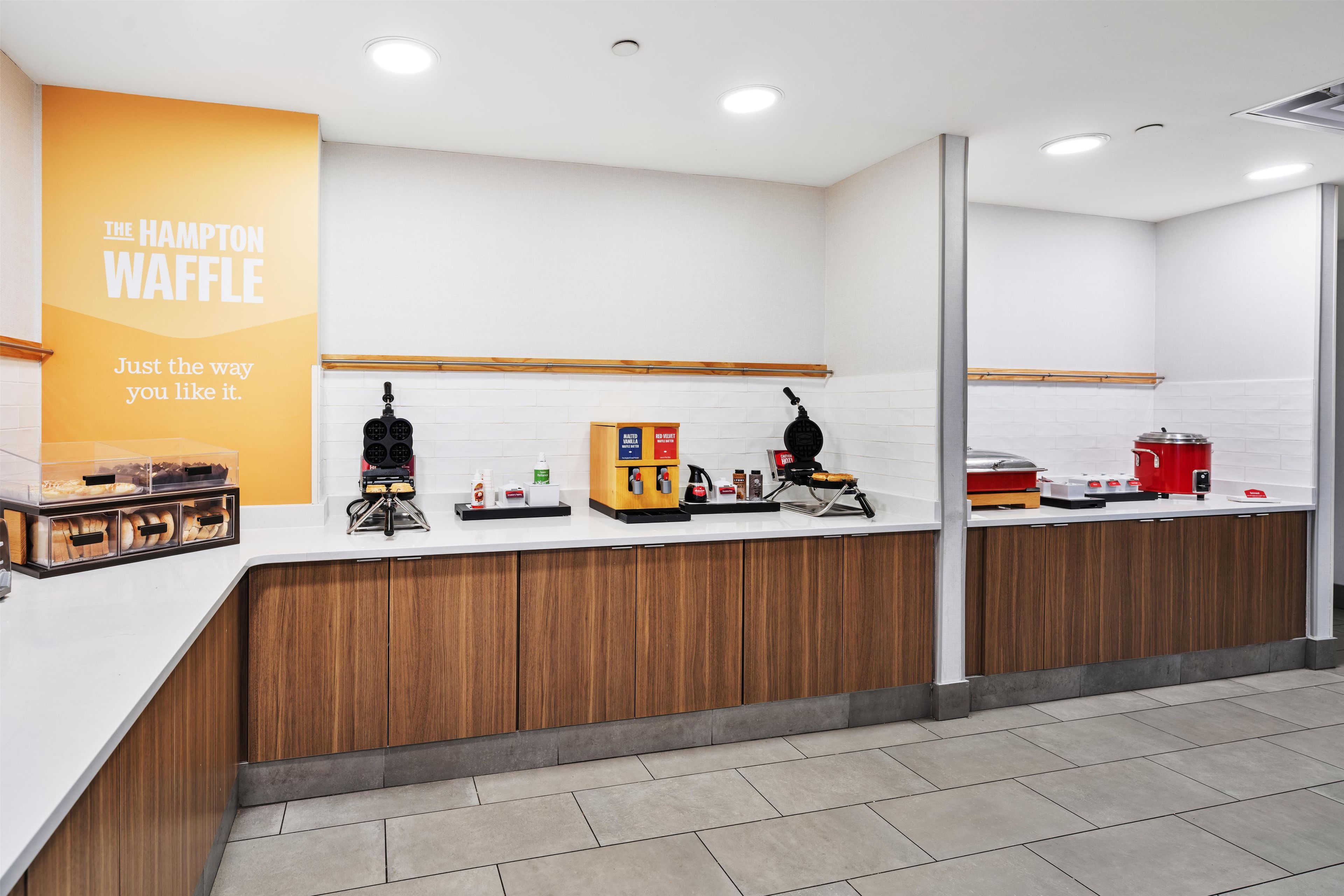 Una cocina moderna y limpia con una estación de gofres, una cafetera y una vitrina con gofres.