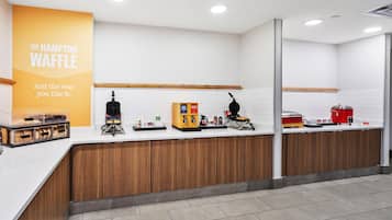 Una cocina moderna y limpia con una estación de gofres, una cafetera y una vitrina con gofres.