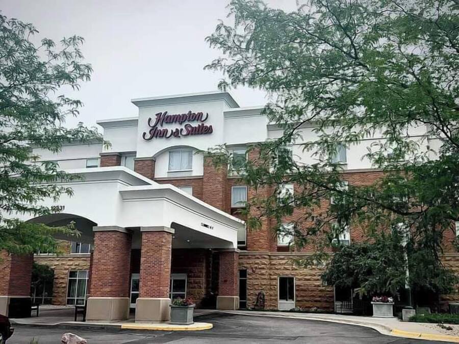 Un hotel Hampton Inn & Suites con fachada de ladrillo, un gran letrero y un estacionamiento.
