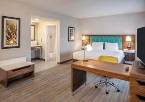A hotel room with a bed, desk, chair, and a bathroom.