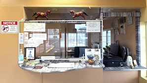 A reception desk with a notice sign, a welcome message, and various informational posters. - Red Carpet Inn & Suites Lima (Lima)