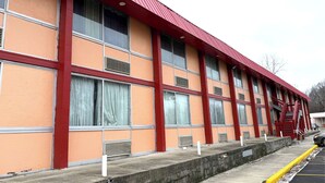 A building with a red roof and orange walls, featuring large windows and a fire escape.