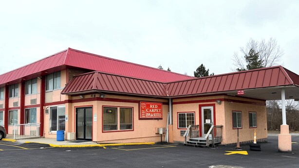 A Red Carpet Inn & Suites building with a red roof and beige walls.