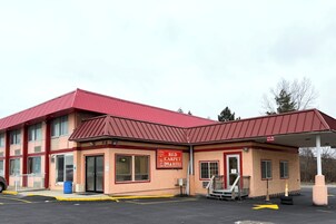 Edificio de Red Carpet Inn & Suites con techo rojo y paredes color beige.