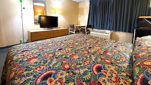 A hotel room with a large bed, a television on a wooden dresser, a desk with a chair, and a window with curtains. - Red Carpet Inn & Suites Lima (Lima)